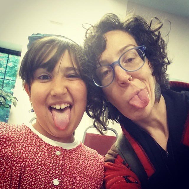 A adult woman and young girl both sticking their tongues out