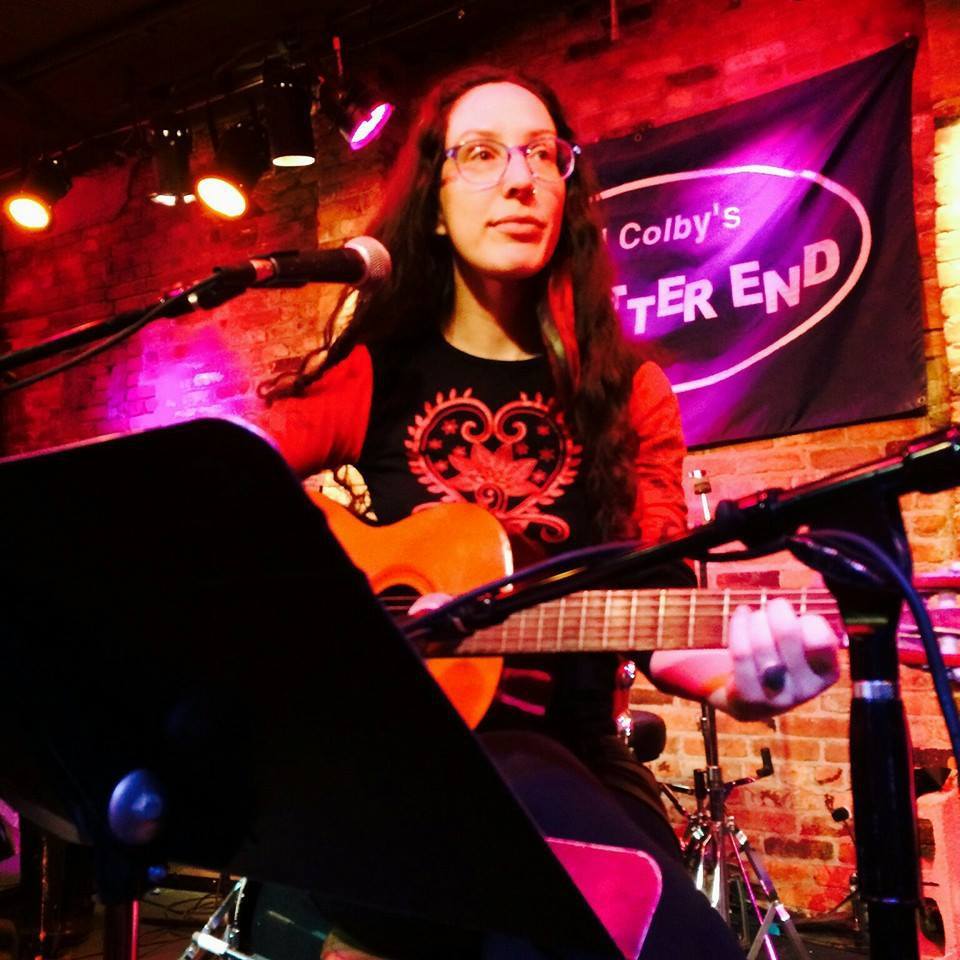 A woman playing guitar on a stage